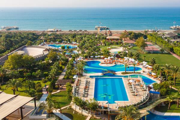 Luftaufnahme des Sherwood Exclusive Lara Resorts mit Swimmingpools, Sonnenliegen und Blick auf das Meer.