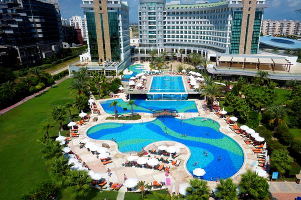 Luftaufnahme des Sherwood Exclusive Lara Hotels mit großen Pools und Sonnenliegen.