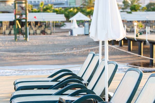 Reihe von Liegestühlen mit Sonnenschirmen auf der Terrasse des Sherwood Exclusive Lara Hotels.