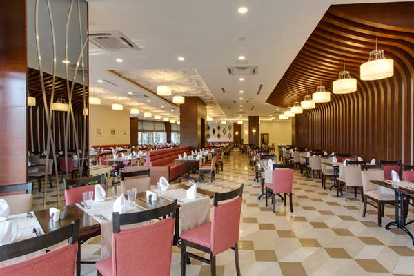 Innenansicht des Restaurants im Sherwood Exclusive Lara Hotel mit gemustertem Boden und elegant eingerichteten Tischen.