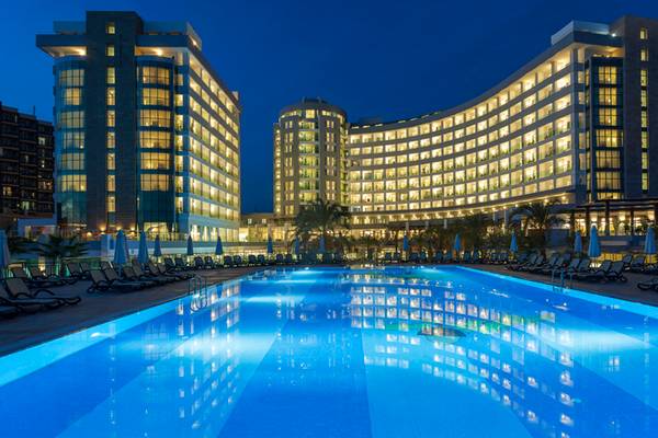Sherwood Exclusive Lara Hotel Pool bei Nacht mit beleuchteten Gebäuden und Sonnenliegen