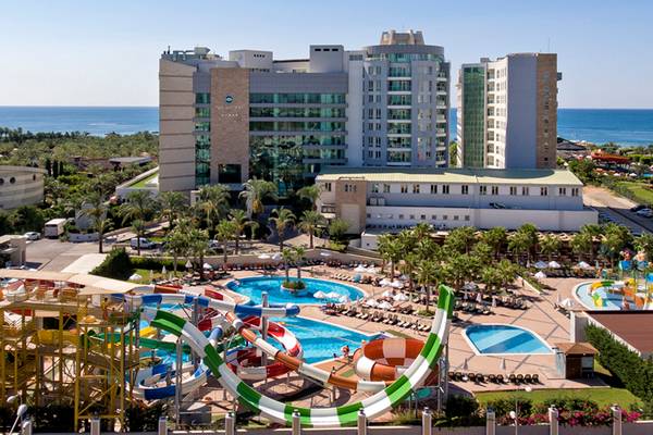Luftaufnahme des Sherwood Exclusive Lara Hotels mit Wasserrutschen und Poolanlage am Meer