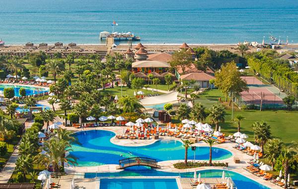Luftaufnahme des Sherwood Exclusive Lara Resorts mit Swimmingpools, Sonnenliegen und Hotels am Meer.