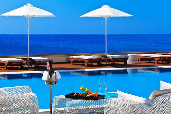 Poolbereich des Boutique 5 Hotel mit Blick auf das Meer, Loungeliegen und Schirme.