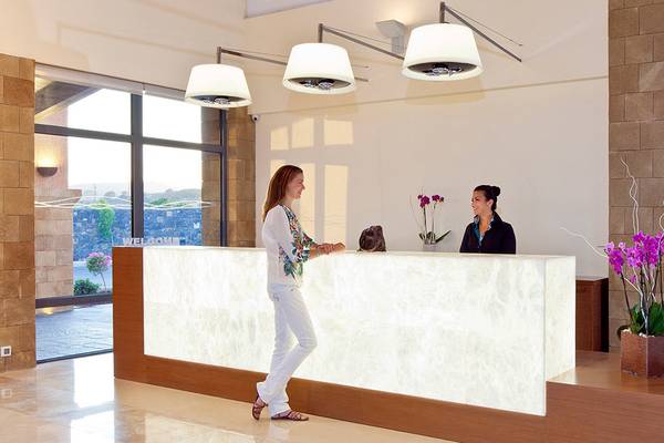 Empfangsbereich im Boutique 5 Hotel & Spa mit einer Rezeptionistin und einer Frau, die an der Rezeption steht.