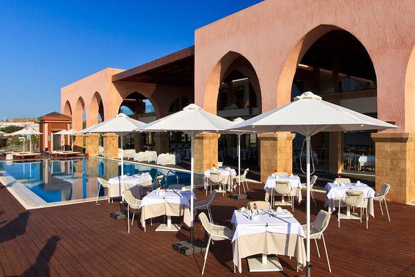 Außenbereich der Boutique 5 Hotel & Spa mit einem Pool, Tischen und weißen Sonnenschirmen.