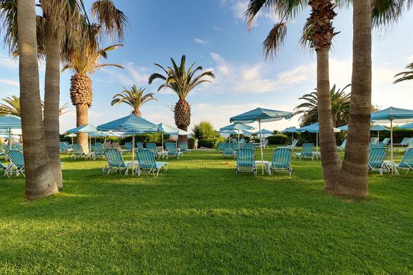 Loungebereich des Creta Star Hotels mit Liegestühlen, Sonnenschirmen und Palmen
