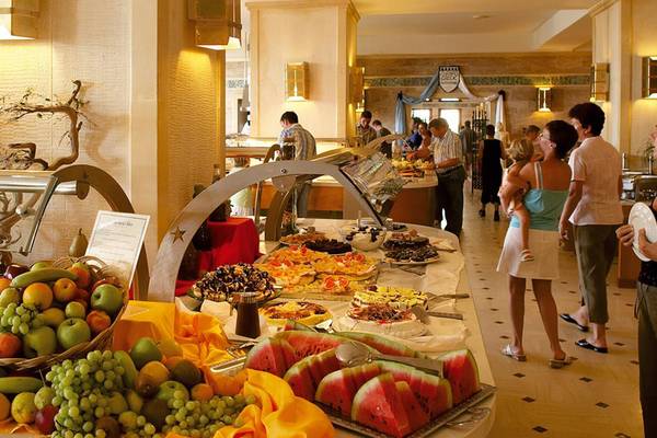 Buffet im Hotel Creta Star mit verschiedenen Desserts, Obst und Menschen, die essen.