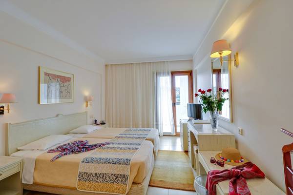 Doppelzimmer im Creta Star Hotel mit zwei Betten, Fernseher, und Rosen im Vasen.