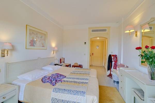 Innenansicht eines Hotelzimmers im Creta Star Hotel mit zwei Betten, Tisch, Lampe und Dekoration.
