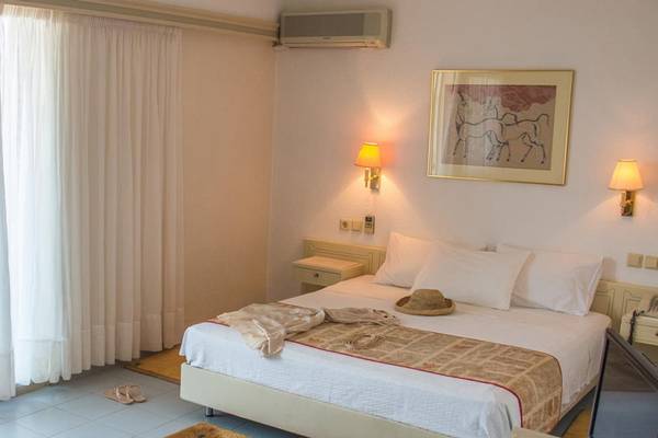 Ein Schlafzimmer im Creta Star Hotel mit einem Bett, einem Tisch, einem Fernseher und einer Lampe.