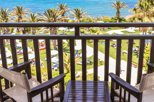 Aussicht vom Balkon des Creta Star Hotels auf den Ozean und den Rasenbereich mit Liegen und Sonnenschirmen.