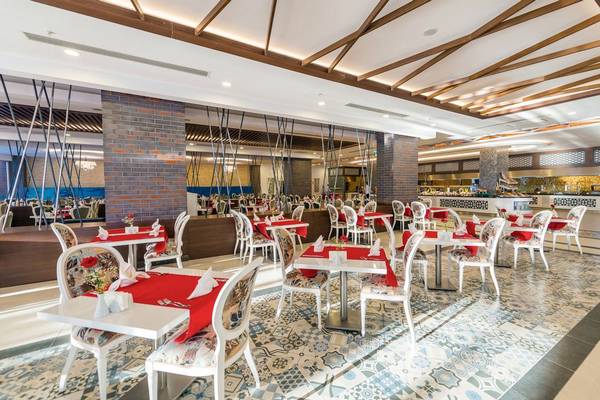 Innenbereich des Dream World Hill Hotels mit mehreren geräumigen Tischen und Stühlen, die für ein Restaurant eingerichtet sind.