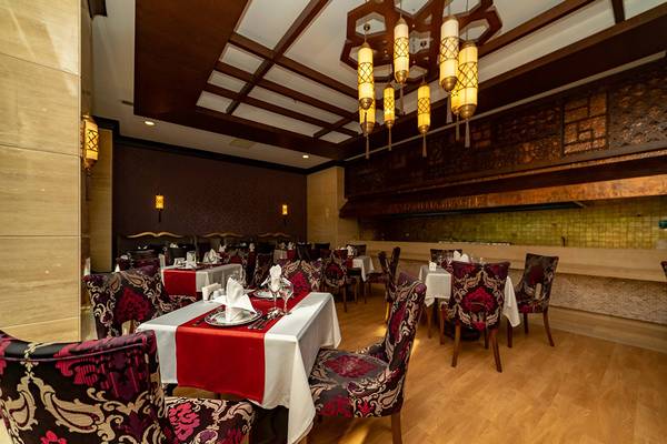 Innenansicht des Restaurants im Seamelia Beach Resort & Spa mit gedeckten Tischen und hängenden Laternen.