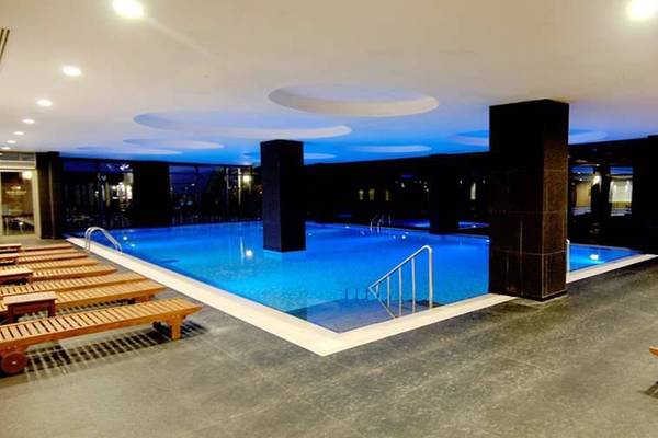Innenpool des Seamelia Beach Resort & Spa mit blauem Wasser und Holzliegen.