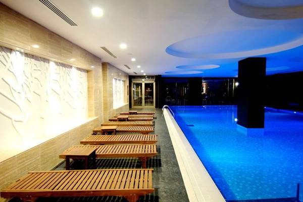 Innenpoolbereich des Seamelia Beach Resort & Spa mit geometrischen Deckenleuchten und Liegestühlen