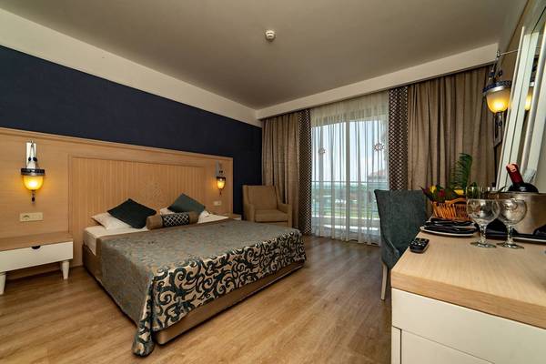 Innenansicht eines Hotelzimmers im Seamelia Beach Resort & Spa mit einem Bett, Stühlen und einem Fenster.