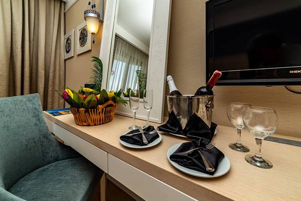 Foto von einem Hotelzimmer mit einem Tisch, einer Flasche Wein und Gläsern.