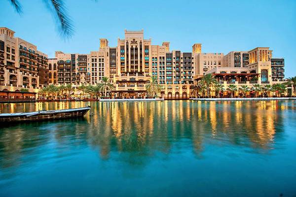 Jumeirah Dar Al Masyaf Hotel am Wasser mit Boot und Palmen im Vordergrund