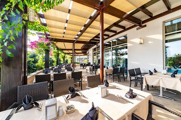 Außenterrasse des Seamelia Beach Resort & Spa mit gedeckten Tischen und Stühlen.