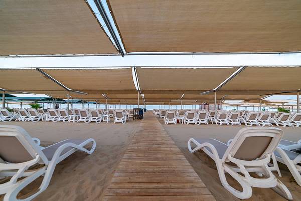 Strand mit vielen weißen Sonnenliegen unter Sonnenschutzdächern am Seamelia Beach Resort & Spa