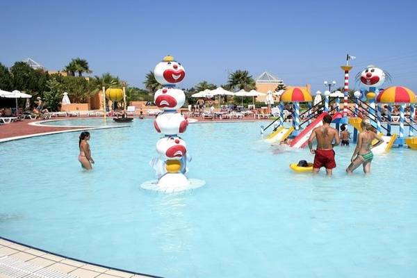 Menschen spielen im Poolbereich des Royal & Imperial Belvedere Hotels, umgeben von bunten Wasserspielgeräten.