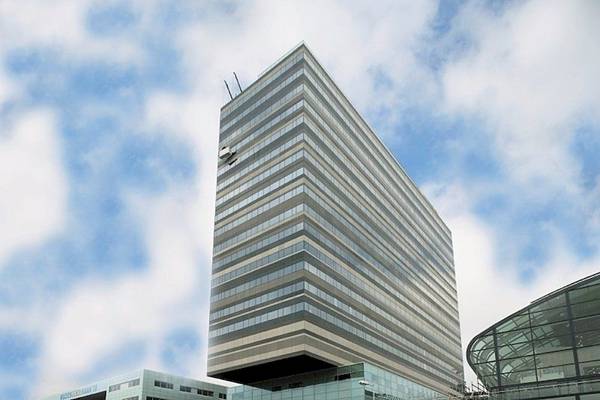 Hochhaus des Mövenpick Amsterdam City Centre Hotels mit blauem Himmel im Hintergrund