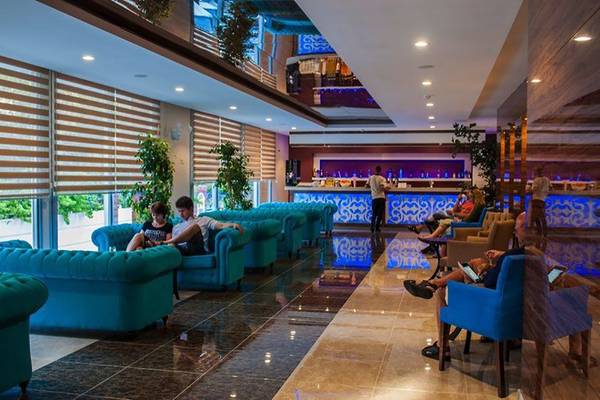 Lounge-Bereich im Sun Beach Park & Spa Hotel mit blauen Couchen, Pflanzen und einer Bar.
