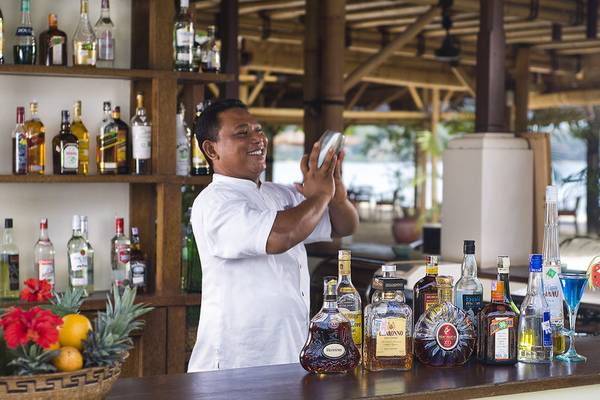 Ein Barkeeper im Jimbaran Puri Hotel, Bali, schüttelt einen Cocktail.