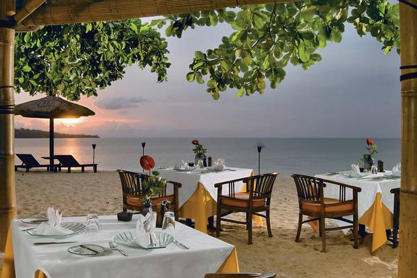 Strandrestaurant im Jimbaran Puri, Bali, mit Tischen und Stühlen, die im Freien serviert werden, mit Blick auf das Meer.