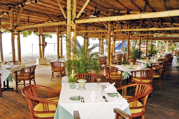 Esszimmer des Jimbaran Puri Hotels in Bali mit Bambusdach und Blick auf den Strand.