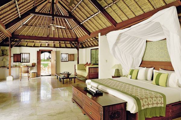 Schlafzimmer im Jimbaran Puri, A Belmond Hotel, Bali mit großem Bett und traditionellem Design.