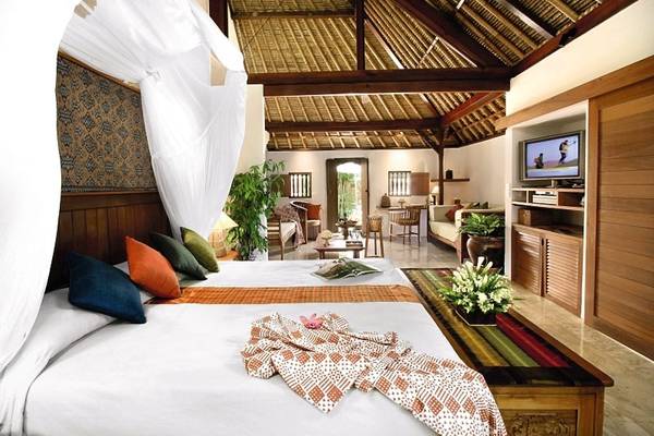 Schlafzimmer im Jimbaran Puri Hotel mit traditioneller Einrichtung und moderner Technik