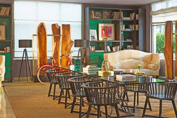Lobby-Bereich des Kimpton Surfcomber Hotels mit Glastisch, Stühlen und Bücherregal.