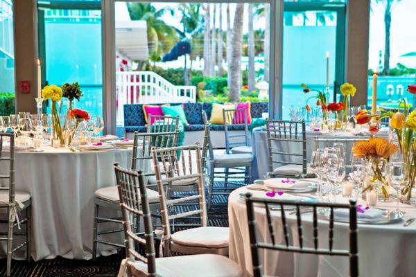 Bankettsaal im Kimpton Surfcomber Hotel mit gedeckten Tischen und bunten Kissen auf der Bank