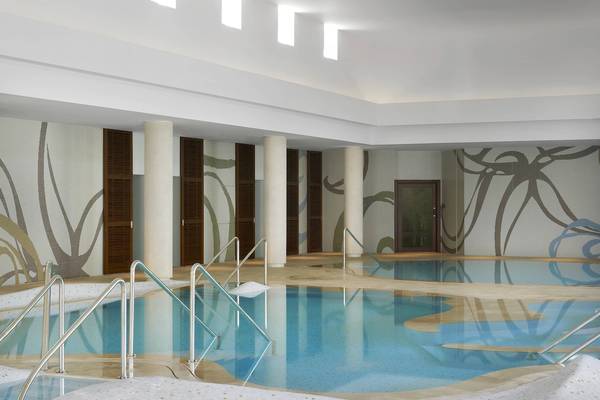 Das Westin Resort, Costa Navarino, zeigt den Innenraum des Pools mit blauem Wasser und künstlerischen Wandverkleidungen.
