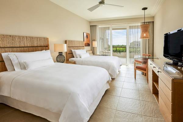 Schlafzimmer im Westin Resort, Costa Navarino mit zwei Betten, Fernseher und Balkon.
