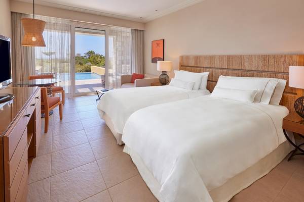 Hotelzimmer im Westin Resort, Costa Navarino mit zwei Betten, Panoramafenster und Swimmingpool-Blick.