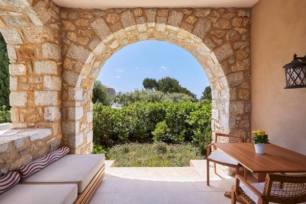 Terrasse mit Sitzecke im Westin Resort, Costa Navarino, mit Blick auf eine gepflegte Gartenlandschaft.