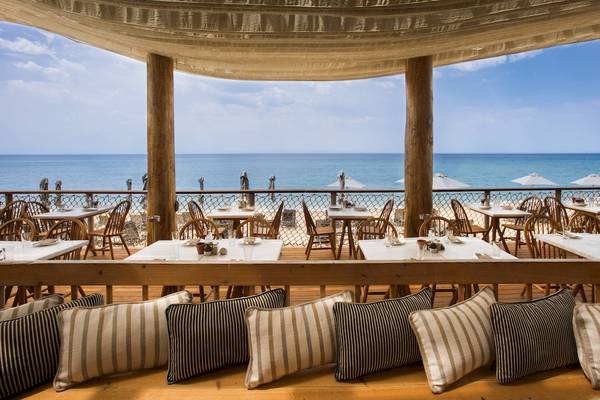 Terrasse des Westin Resorts Costa Navarino mit Blick auf das Meer und weiße Tische.