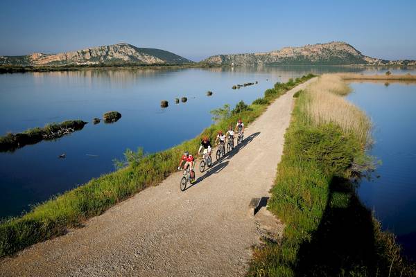 Radfahrer am See vor Hintergrund des Westin Resorts Costa Navarino