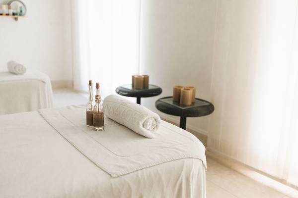 Massageraum im Westin Resort, Costa Navarino mit zwei Massageliegen, Handtüchern und Flaschen