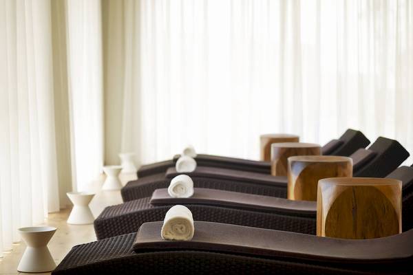 Reihe von Loungeliegen im Spa-Bereich des Westin Resorts, Costa Navarino, mit weißen Handtüchern und Holzfußstühlen.