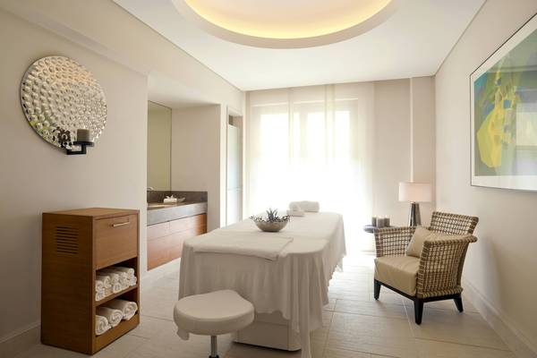 Massageraum im Westin Resort, Costa Navarino mit Liege, Kerzen und Deko.