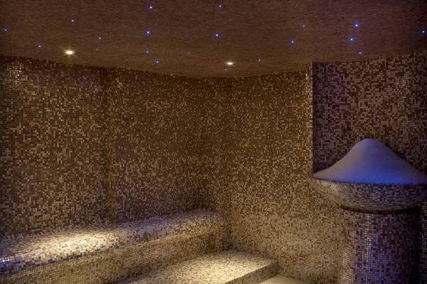 Innenansicht der Sauna im Westin Resort, Costa Navarino mit Mosaikwänden und Sternenlicht.