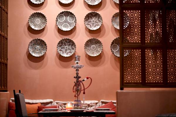 Tisch im Westin Resort Costa Navarino mit einer Narghile und dekorativen Tellern an der Wand.