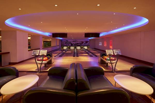 Bowlinghalle im Westin Resort, Costa Navarino mit Bowlingbahnen, leuchtenden Farben und Sofas.
