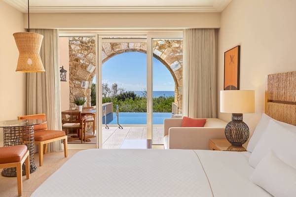 Luxuriöses Schlafzimmer mit Meerblick im Westin Resort, Costa Navarino, zeigt ein großes Bett, Wohnzimmerbereich und Terrasse.