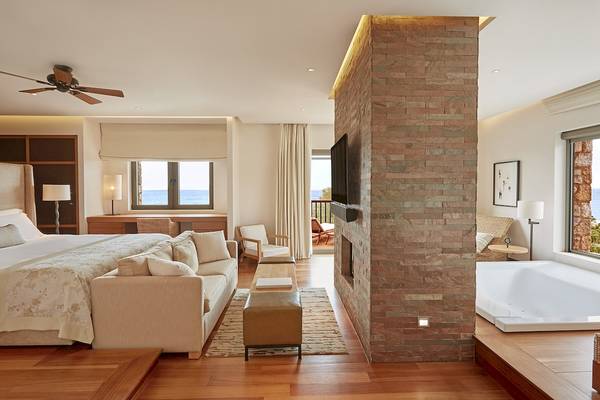 Schlafzimmer im Westin Resort, Costa Navarino mit großer Bett, Wohnzimmerbereich und Blick aufs Meer.