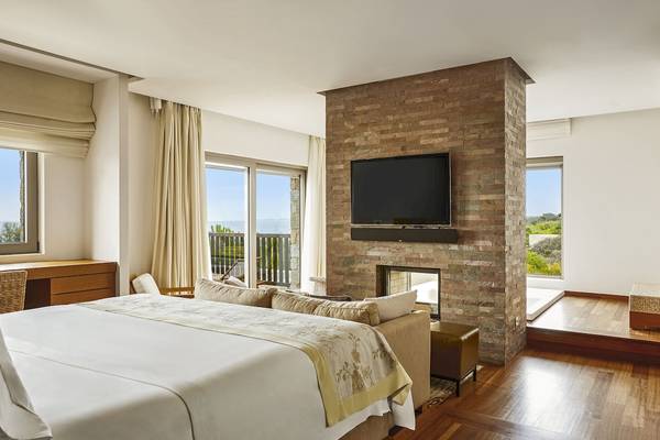 Schlafzimmer im Westin Resort, Costa Navarino mit großem Bett, Sofa und Fernseher.